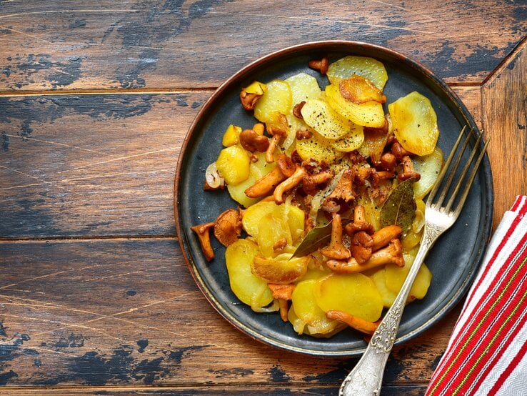 Aus der Vogelpersektive: Ein Teller Bratkartoffeln mit frischen Pfifferlingen. Auf dem Teller liegt ein Gabel. | © Shutterstock / Liliya Kandrashevich