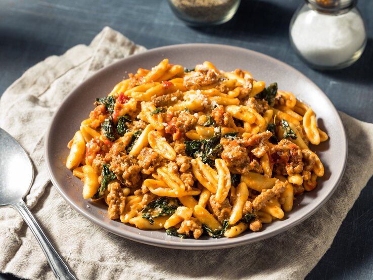 Pasta in tomatiger Hackfleisch-Schmand-Soße auf weißem Teller. 