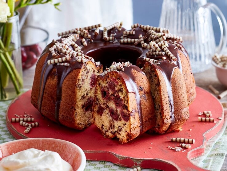 Auf einem Teller steht ein Eierlikör-Kirsch-Hupf. Er ist mit Schokoröllchen verziert.