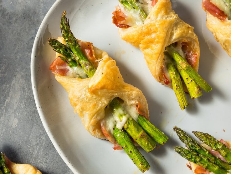 Spargel-Päckchen mit Schinken und Käse auf weißem Teller.  | © Getty Images/bhofack2