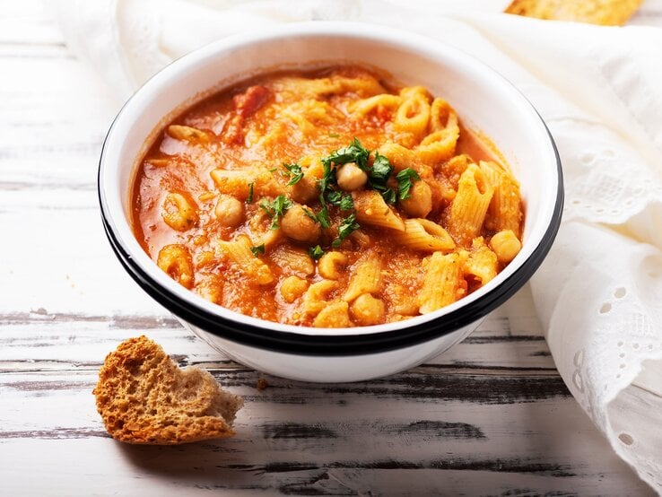 Eine Schüssel Pasta e Ceci, italienischer Nudeleintopf mit Kichererbsen, garniert mit Petersilie.