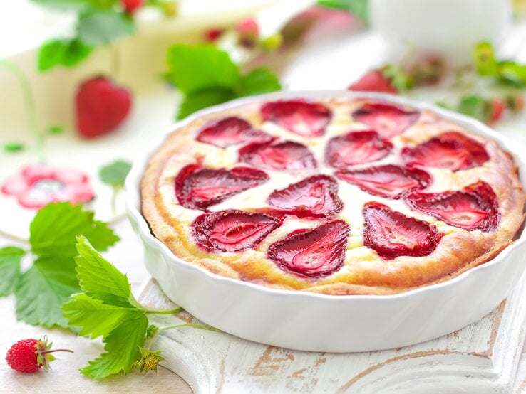 Erdbeer-Quark-Auflauf mit Grieß in weißer Auflaufform in frühlingshaftem Ambiente. | © Getty Images/YelenaYemchuk