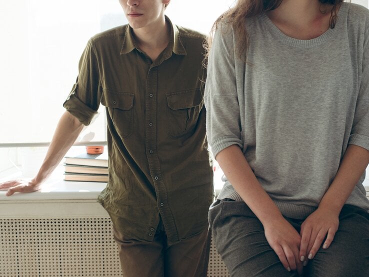 Oberkörper eines Pärchens, die in Distanz zueinander stehen und auf ein Scheitern der Beziehung deuten. 