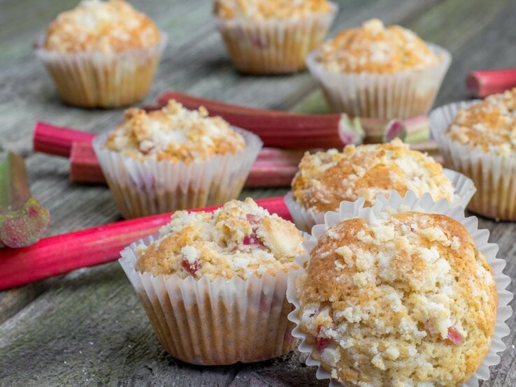 Mehrere Muffins auf einem Holztisch mit Rhabarberstangen. | © Shutterstock/ Jaromir Klein