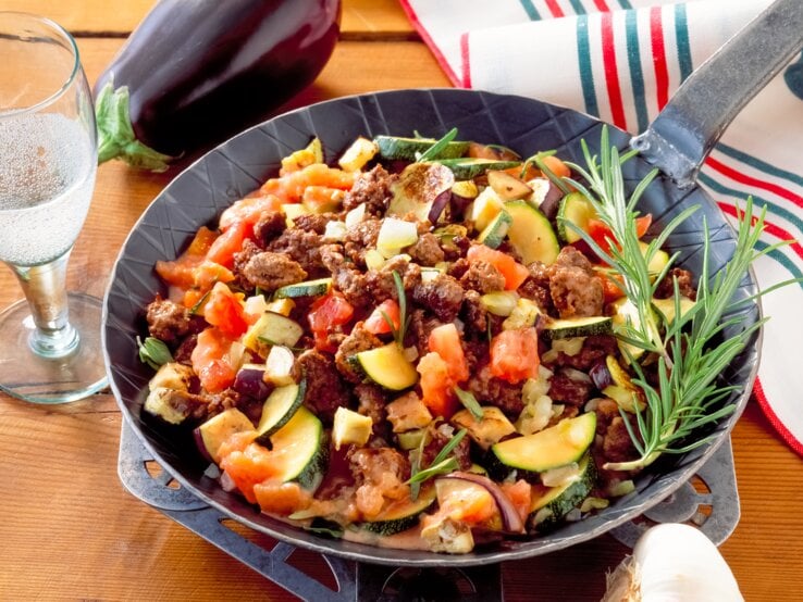 Zucchini-Hackfleisch-Pfanne mit Tomaten auf Holztisch. 