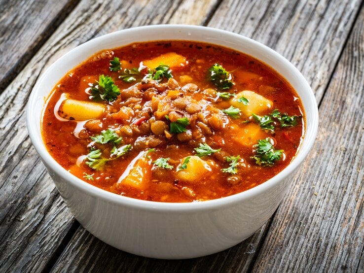 Eine Schüssel Kokos-Kichererbsensuppe mit Kartoffeln, Tomaten und gehacktem Koriander.