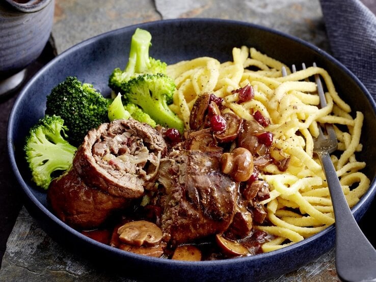 Auf einem tiefen Teller liegt eine Portion Rinderrouladen mit Pilzen und Spätzle. Sie wird mit Brokkoli serviert. | © EAT CLUB / Isabell Triemer