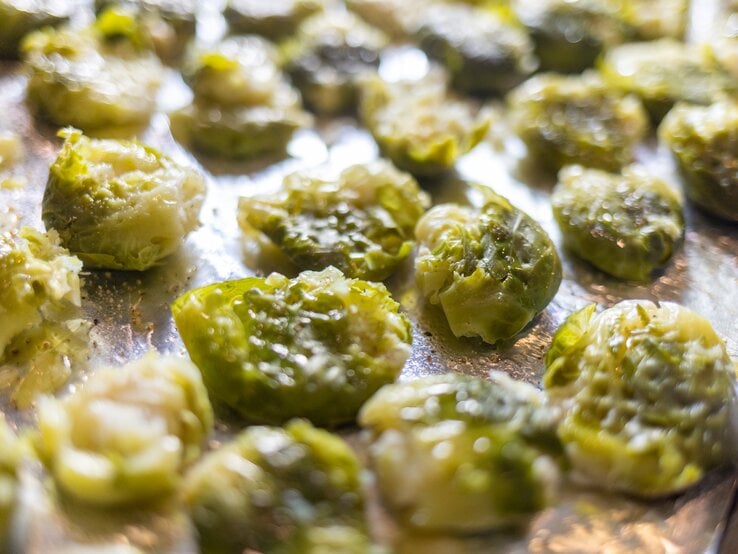 Smashed Rosenkohl auf einem Backblech mit Backpapier. | © Getty Images/ carlofranco