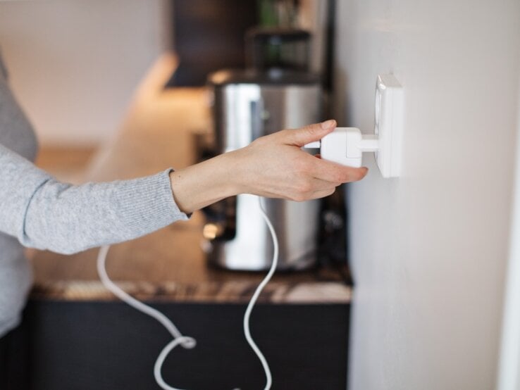 Eine Frau steckt einen Stecker in eine Steckdose.
