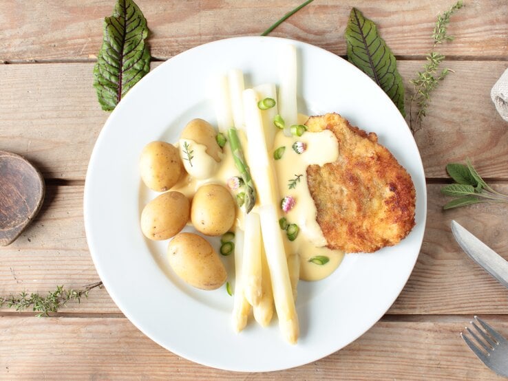  Spargel mit Schnitzel in frühlingshafter Cremesoße mit Kartoffeln auf Holztisch