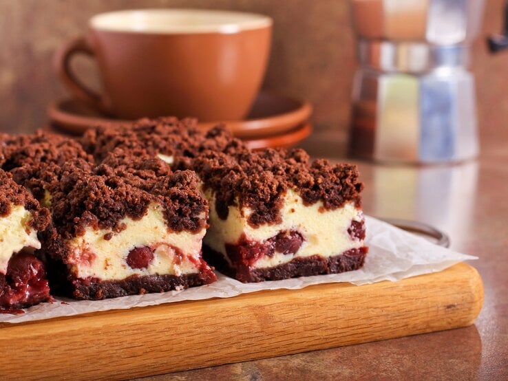 Kirsch-Käsekuchen mit Schokostreusel auf Holzbrett. | © Getty Images/manyakotic
