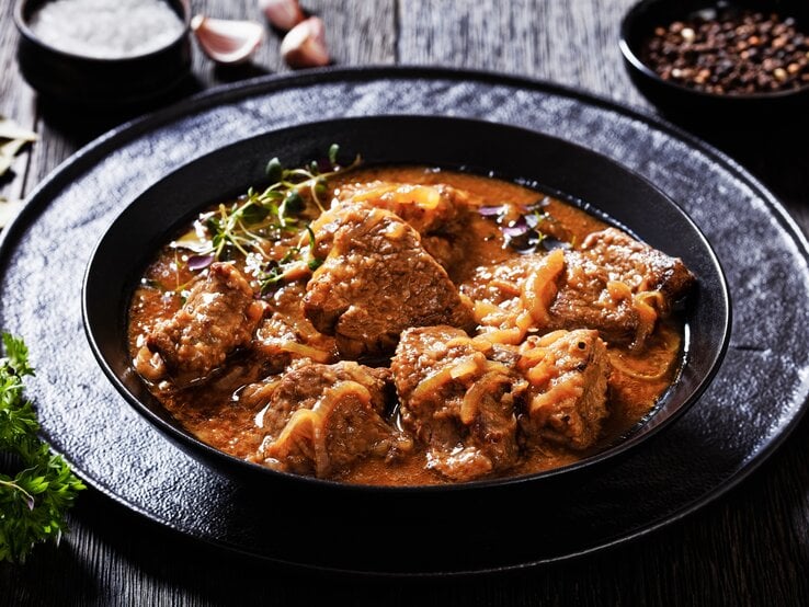 Ein schwarzer Teller mit flämischem Rindergulasch.