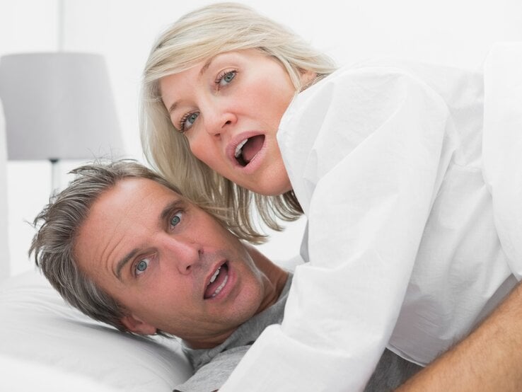 Paar in einem Bett. Beide schauen überrascht oder verwundert in die Kamera, mit weit geöffneten Augen und leicht geöffneten Mündern. | © Getty Images / Wavebreakmedia Ltd