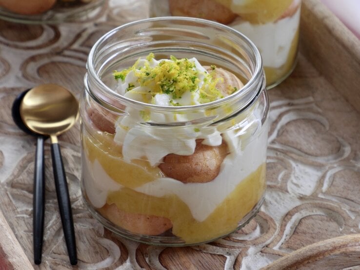 Ein Glas Zitronen-Tiramisu mit Zitronenzeste und Limettenabrieb dekoriert.
