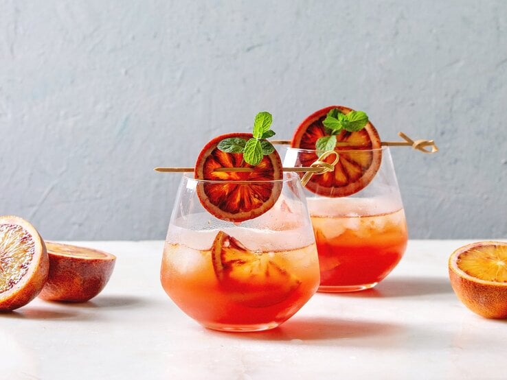 Zwei Gläser Sarti Spritz mit Orangenscheiben dekoriert.