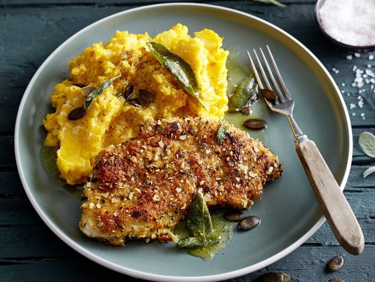 Knusper-Schnitzel mit Kürbisstampf auf Teller, belegt mit Salbei und Kürbiskernen.  | © EAT CLUB/Isabell Triemer