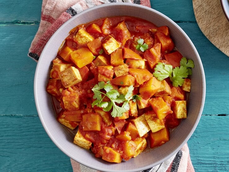 Ein Teller Kürbis-Tofu-Ragout mit Petersilie bestreut, Draufsicht.