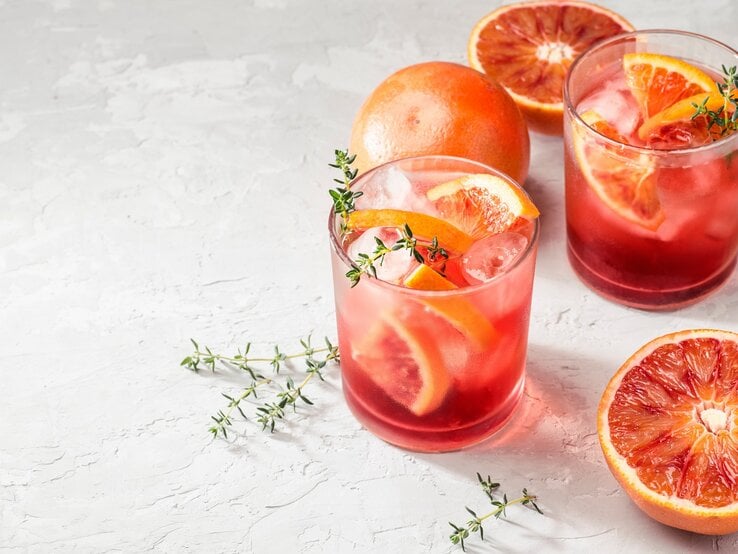 Zwei Gläser mit Campari Spritz auf hellem Untergrund.