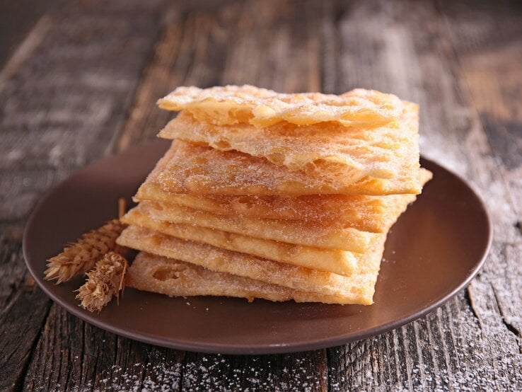 Ein Stapel mit französischem Schmalzgebäck auf einem braunen Teller.