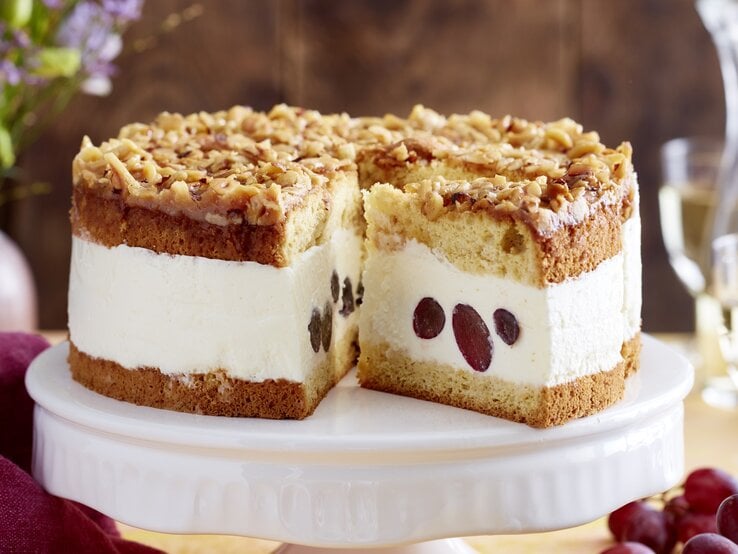 Angeschnittene Weißwein-Trauben-Torte auf weißem Tortenteller, verschwommener Hintergrund.  | © EAT CLUB / Isabell Triemer 