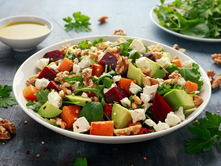 Ein weißer tiefer Teller mit einer Kürbis-Bowl mit Avocado und Feta.