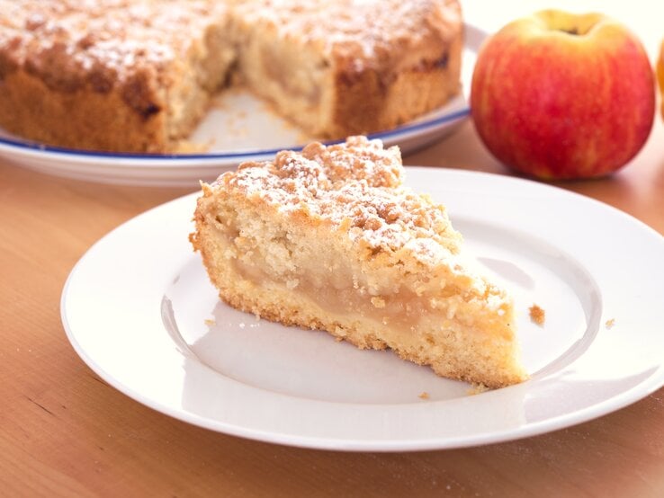 Ein Stück Apfelkuchen mit Streusel auf einem weißen Teller.  | © AdobeStock