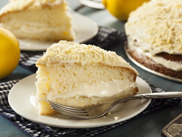 Zitronencremetorte angeschnitten mit einem einzelnen Stück auf einem Teller.  | © Getty Images/bhofack2