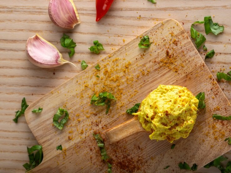 Dattel-Curry-Dip auf Holzbrett, daneben einige Zutaten. | © Adobe Stock/Sebastian Radu