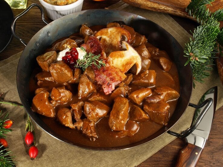 Eine gusseiserne Pfanne mit dem Hirschrahm auf einem Leinentuch mit Tannendeko.