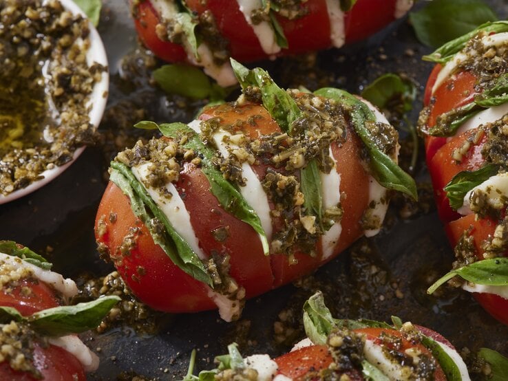 Fächer-Tomaten a la Caprese mit Knoblauch-Pesto serviert.