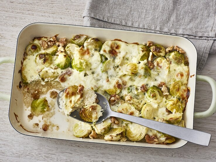 Ofencouscous mit Rosenkohl, Walnüssen und überbackenem Blauschimmelkäse in einer Form auf hellem Untergrund  | © Stockfood