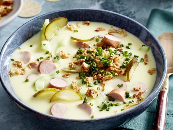 In einer Schüssel ist eine Hotdog-Suppe angerichtet. Sie ist mit Schnittlauch und Röstzwiebeln verfeinert.