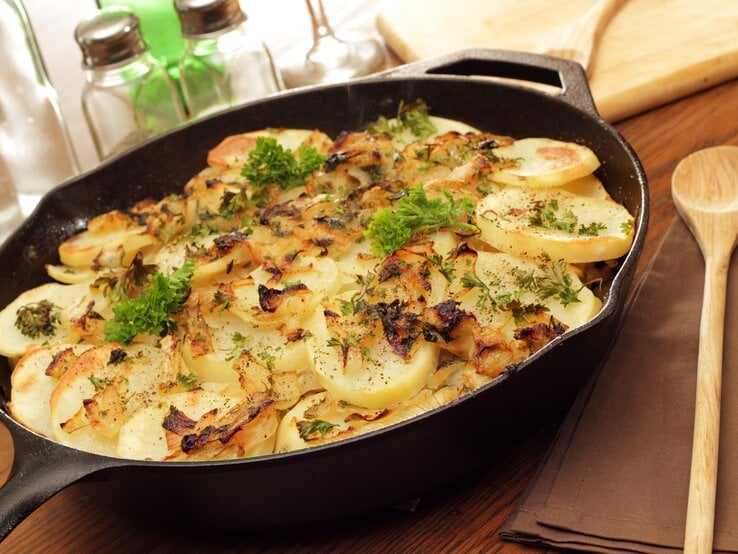 Kartoffeln Lyonnaise in gusseiserner Pfanne auf Holz.  | © Getty Images/wsmahar