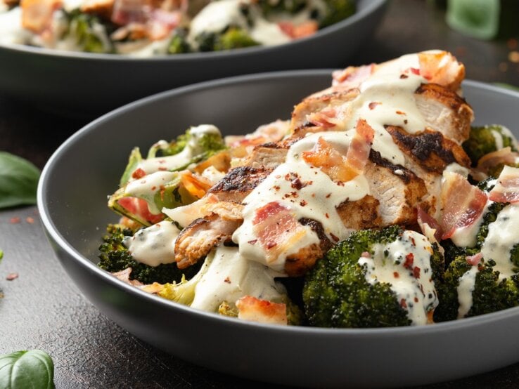 Ein weißer tiefer Teller mit dem Ofenhähnchen und Brokkoli.