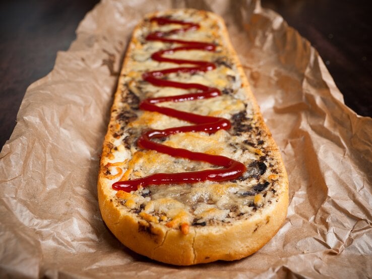 Polnisches Baguette überbacken mit Pilzen, Zwiebeln und Käse, garniert mit Ketchup. | © Shutterstock/kreatorex