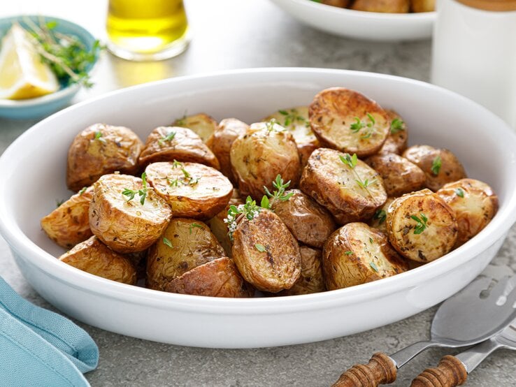 Eine weiße Schüssel mit gebackenen Kartoffeln und Thymian.  | © Getty Images/YelenaYemchuk