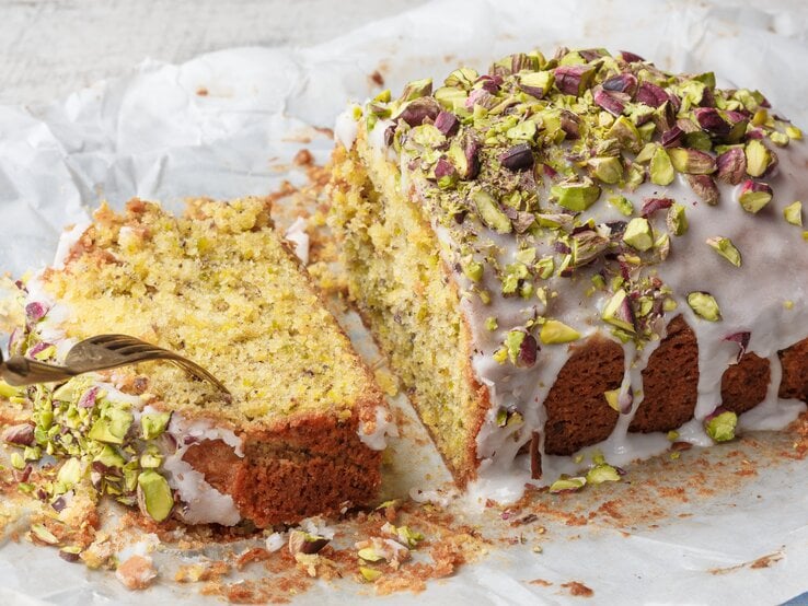 Ein angeschnittener Pistazien-Zitronenkuchen aus der Kastenform.