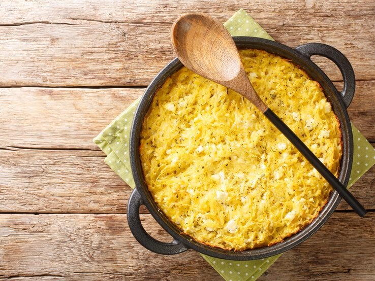 Gusseiserne Pfanne gefüllt mit Patatnik auf hölzernem Untergrund. 