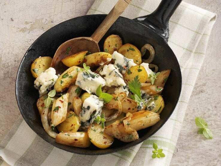 Draufsicht: eine Kartoffel-Spargel-Pfanne mit Roquefort auf einem Küchentuch.