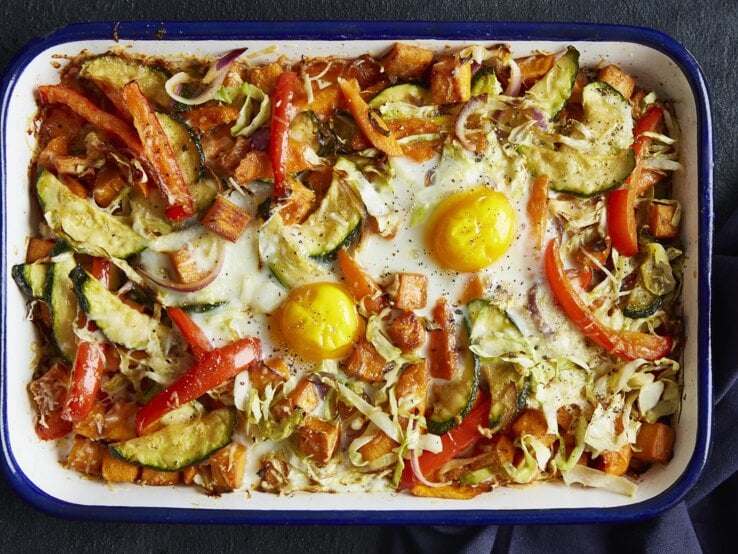 Draufsicht: Eine weiße Form in dem ein Gemüseauflauf mit Spiegeleiern ist.