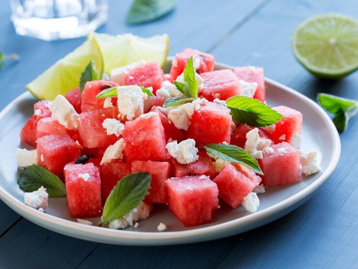 Ein Melonen-Feta-Salat auf einem Teller, stehen auf einem Tisch ist zu sehen.