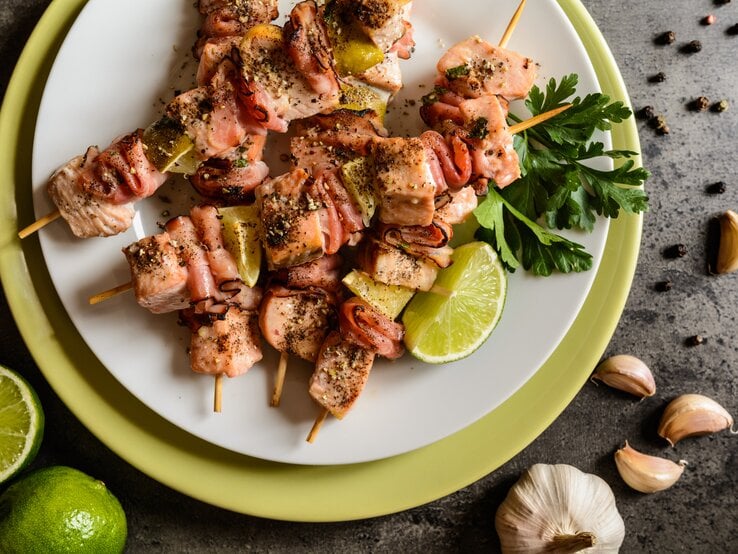 Mehrere Lachsspieße mit Limette auf einem weißen Teller.  | © iStock/ NoirChocolate