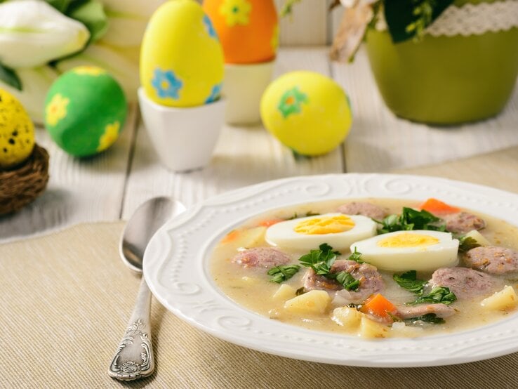 Ein Teller mit der Suppe auf einem hellen Holztisch und Oster-Dekoration.  | © iStock/ iko636