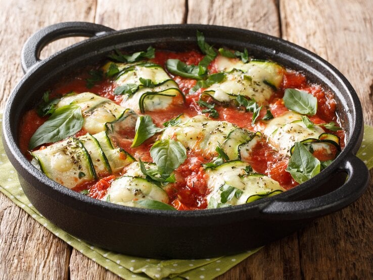 schwarze gusseiserne Pfanne gefüllt mit Zucchini, Feta und Tomatensoße.  | © iStoc.com/ALLEKO