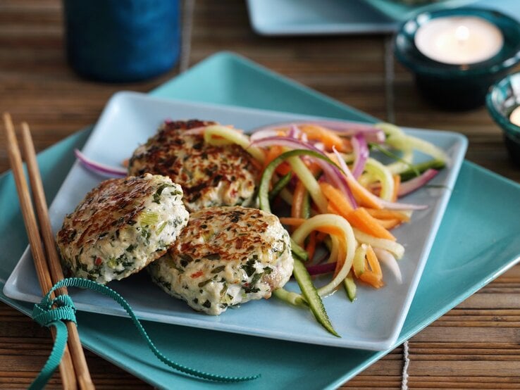 Drei Frikadellen auf einem weißen eckigen Teller und dunklem Holztisch.