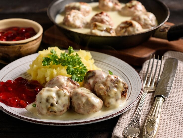 Rustikaler Teller mit Kartoffeln, Preiselbeersoße, Hackbällchen "Köttbullar" und cremiger Soße.  | © iStock/iko636