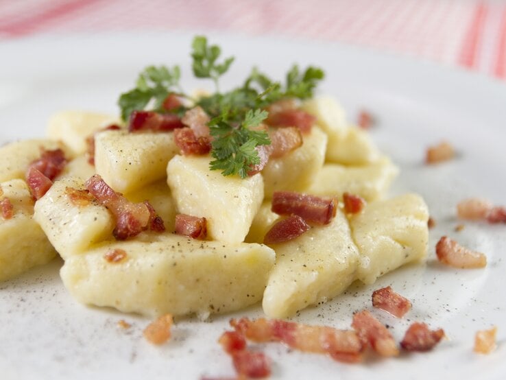 Polnische Klöße mit gebratenem Speck auf Teller.  | © iStock/eyecon