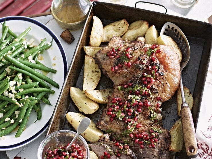 Lammbraten mit Granatapfelkernen und Gemüse. Alles auf einem Tisch arrangiert und von oben fotografiert.