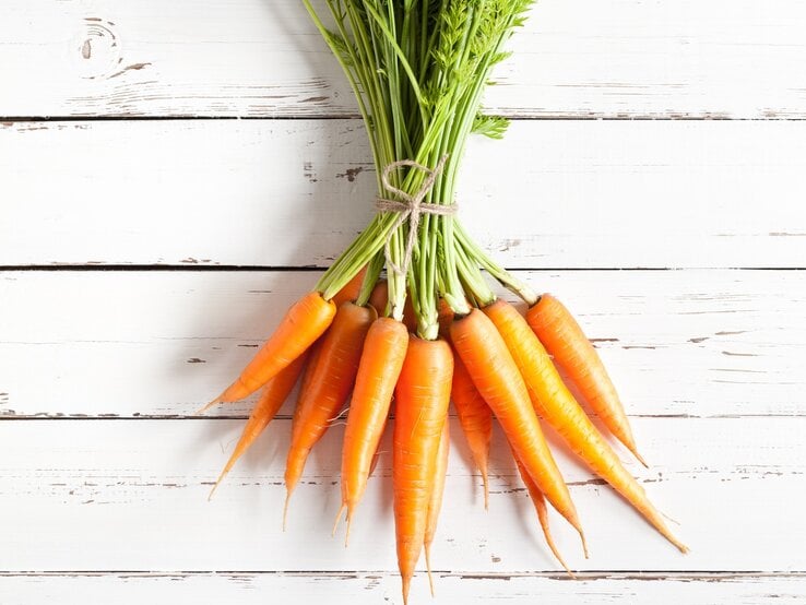 Bund Karotten auf weißem tisch | © iStock/xxmmxx 