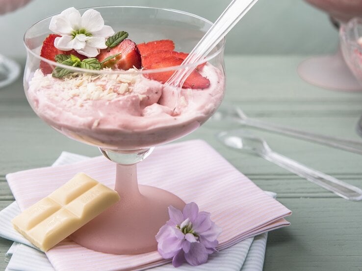 Draufsicht, eint schräg von oben: Eine weiße Schokoladenmousse mit Mascarpone und Erdbeeren in einem Glas.